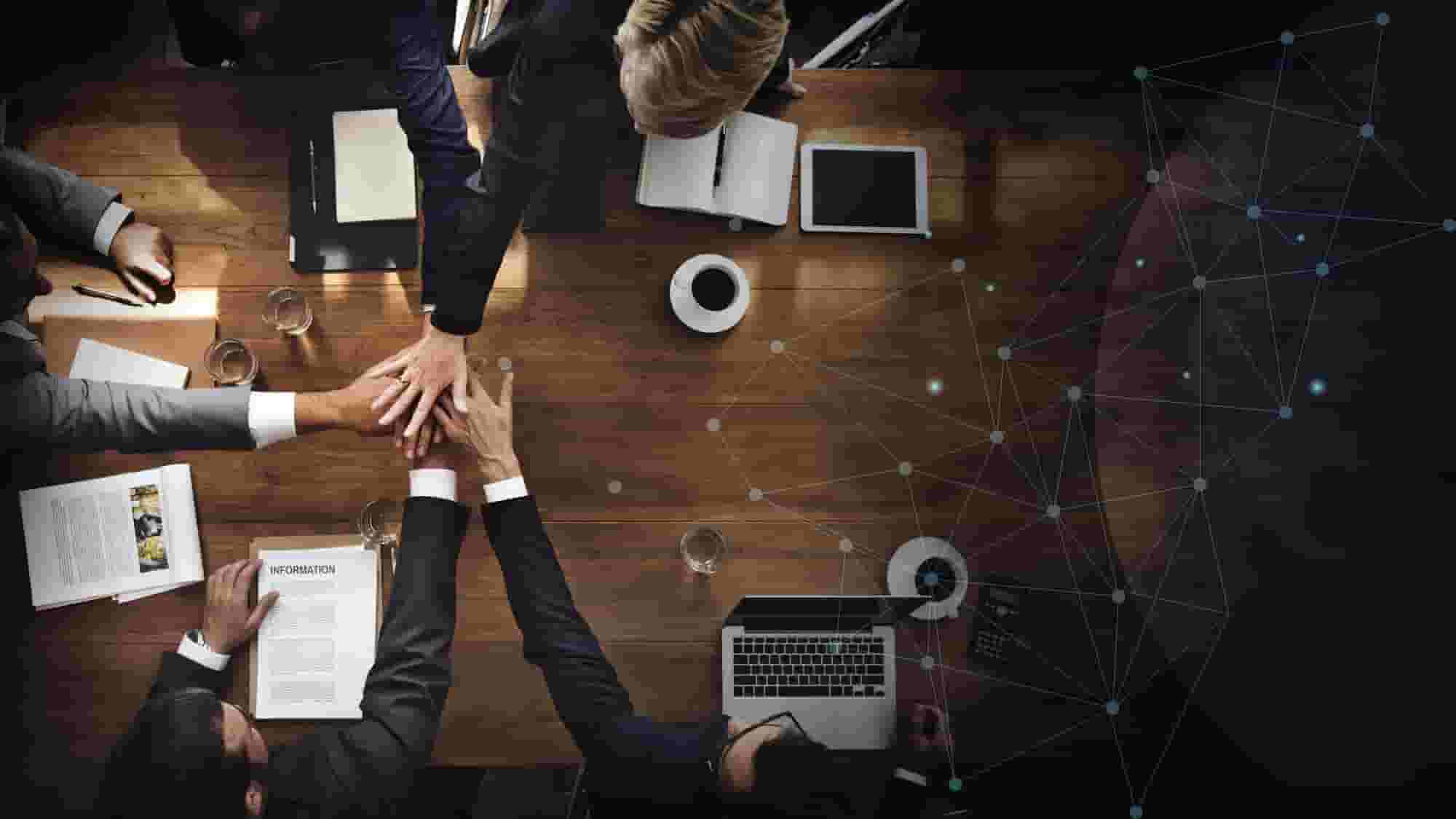 A group of business people holding hands around a table.